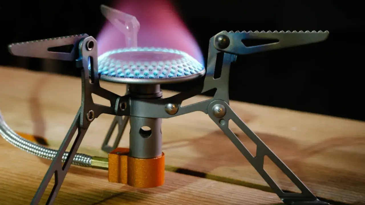 Estufa portátil sin electricidad ni gas, con llama azul y púrpura, ideal para acampar.