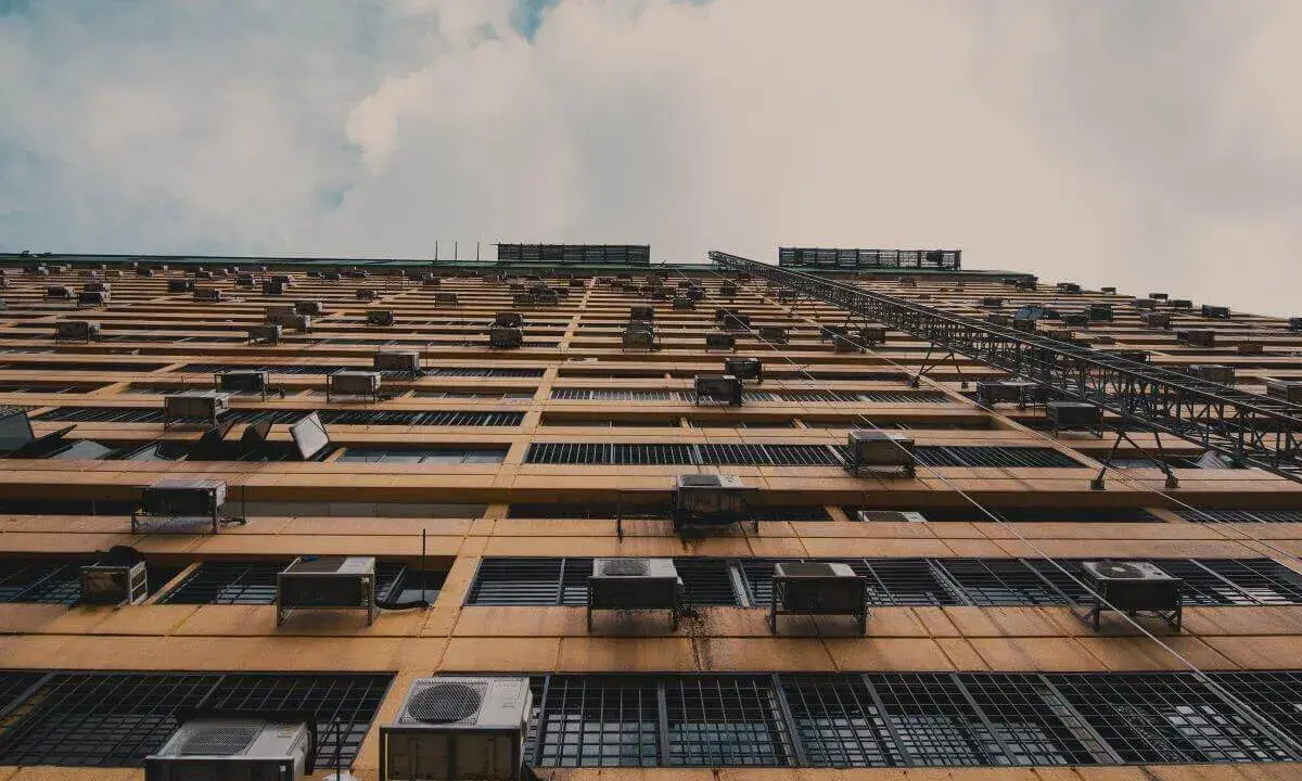 Fachada de edificio con múltiples unidades exteriores de aire acondicionado, mostrando dónde colocar la unidad exterior del aire acondicionado en cada ventana.