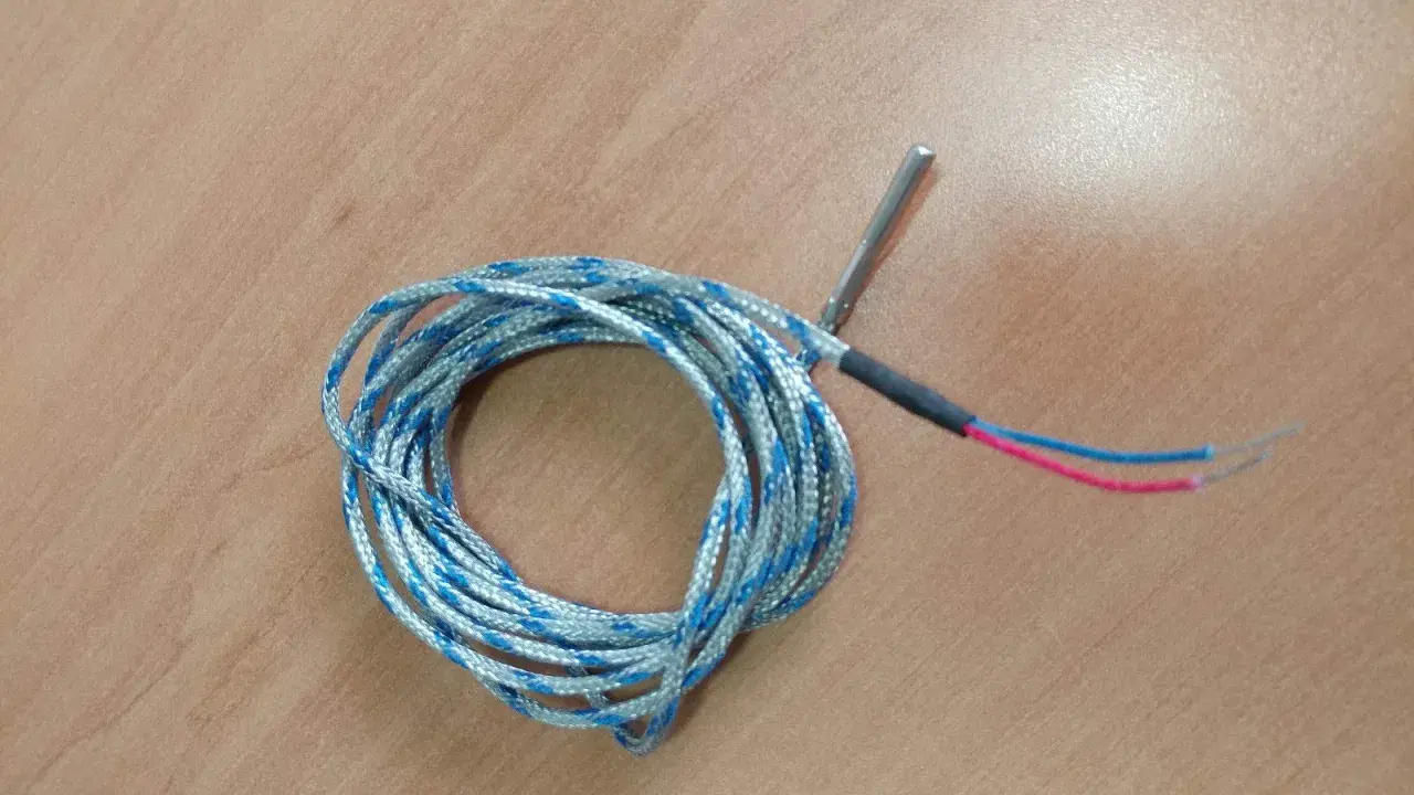 Sonda de temperatura para estufa de pellets, posiblemente indicando un fallo. Cable enrollado con punta metálica y cables rojo y azul.