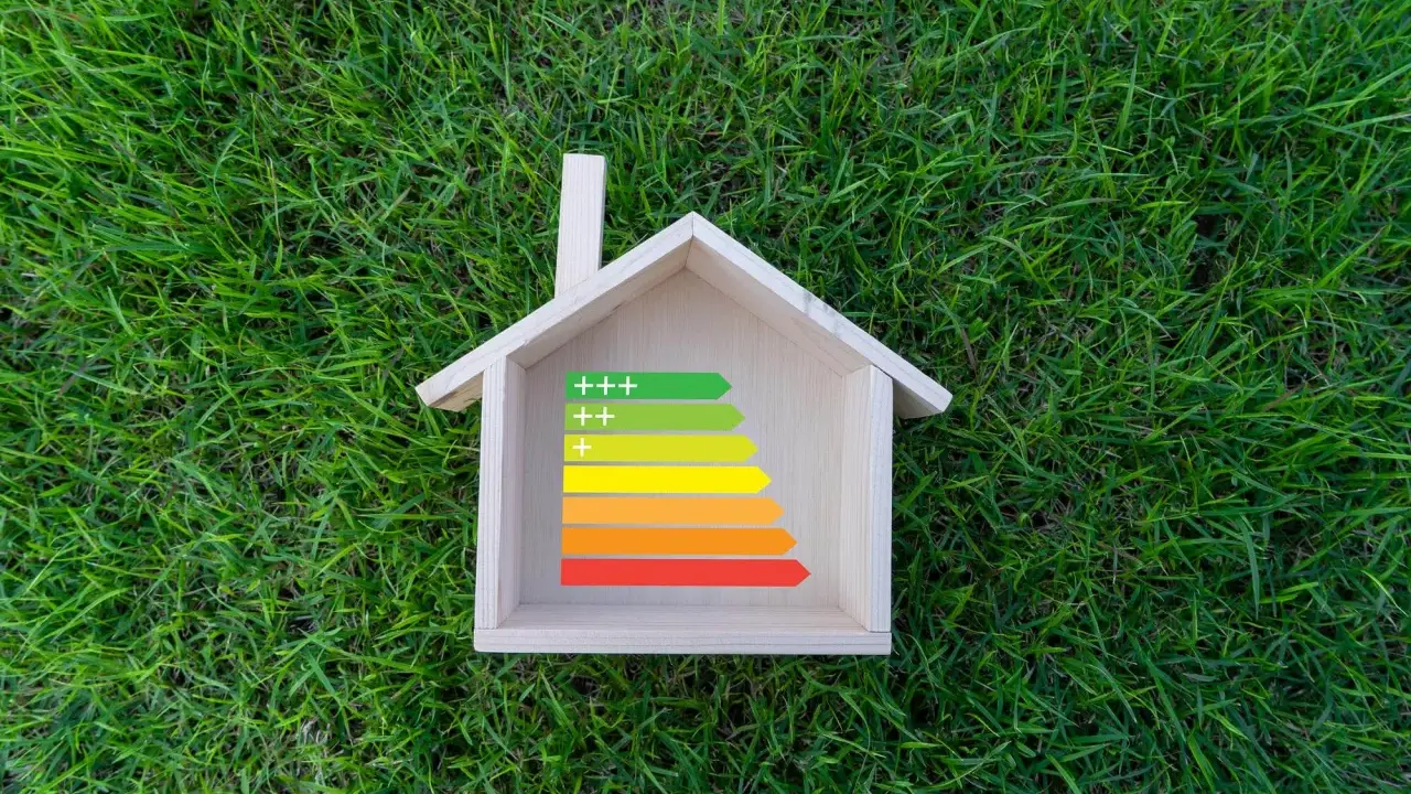 Casa de madera sobre césped con etiqueta de eficiencia energética, ideal para calefacción sostenible.