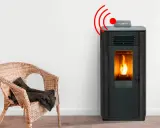 Estufa de pellets con llama encendida y señal de alarma. Junto a una silla de mimbre con manta.