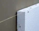 Instalación de aislamiento térmico para aislar tubos de calefacción exterior. Una línea guía de color amarillo ayuda a colocar el poliestireno.