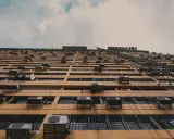 Fachada de edificio con múltiples unidades exteriores de aire acondicionado, mostrando dónde colocar la unidad exterior del aire acondicionado en cada ventana.