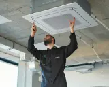 Técnico instala unidad de aire centralizado en el techo.