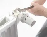 Ajustando el termostato de un radiador. Averigua cuanto cuesta una hora de calefacción de gas natural para optimizar tu consumo.