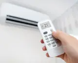 Mano ajustando el control remoto del aire acondicionado a 21°C, modo "Cooling". ¡Así se logra un ambiente fresco y agradable!
