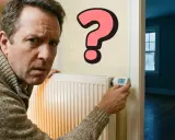 Hombre confundido mira un radiador con un gran signo de interrogación rosa, preguntándose como apagar la calefacción.