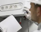 Técnico revisa una caldera de condensación, anotando detalles en su libreta.