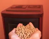 Manos sostienen un puñado de pellets, combustible ecológico para estufas.