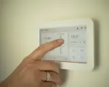Dedo interactúa con un termostato modulante, ajustando la temperatura a 19,5°C.