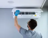 Hombre con guantes azules revisa filtros de aire acondicionado. Quizás el **ruido aire acondicionado** se deba a esto.