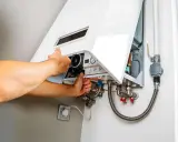 Man checks a gas boiler that won't ignite. He opens the cover to inspect the internal components.