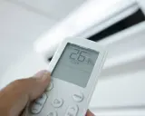Mando a distancia de aire acondicionado mostrando 26°C en modo "Cool". El modo "Dry" deshumidifica el aire.