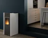 Estufa de pellets sin salida de humos con llama encendida, junto a una barra de cocina moderna.