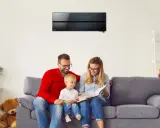 Familia feliz en el sofá, disfrutando de un momento tranquilo bajo el aire acondicionado de bajo consumo.