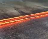 Dos espirales incandescentes, demostrando el efecto Joule en una caldera, brillan con un naranja intenso sobre una superficie oscura y agrietada.