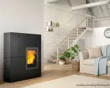 Estufa de pellets negra con fuego encendido, junto a escaleras y sofá. Ideal para un esquema de instalación de hidroestufas de pellets.