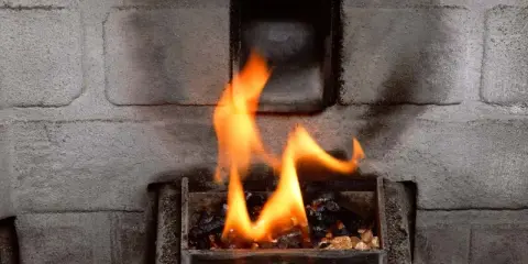 Llamas naranjas bailan sobre pellets en la estufa. El fondo de ladrillo gris sugiere que la alarma 6 estufa pellet está funcionando.