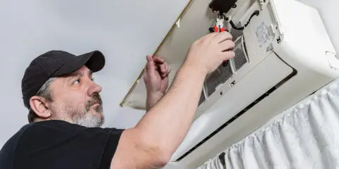 Técnico revisa un aire acondicionado. ¿Cuanto dura un aire acondicionado? El mantenimiento es clave para su longevidad.
