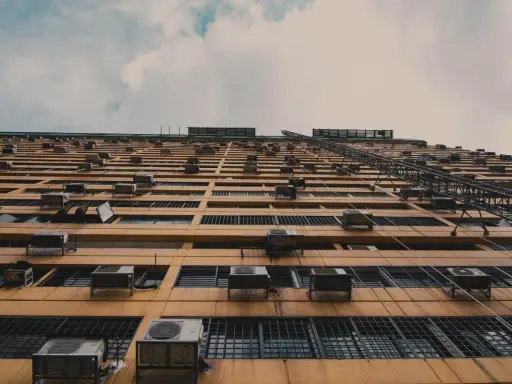 Fachada de edificio con múltiples unidades exteriores de aire acondicionado, mostrando dónde colocar la unidad exterior del aire acondicionado en cada ventana.