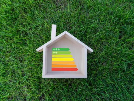 Casa de madera sobre césped con etiqueta de eficiencia energética, ideal para calefacción sostenible.