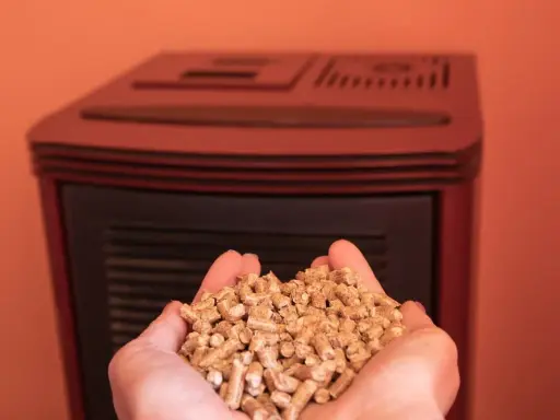 Manos sostienen un puñado de pellets, combustible ecológico para estufas.