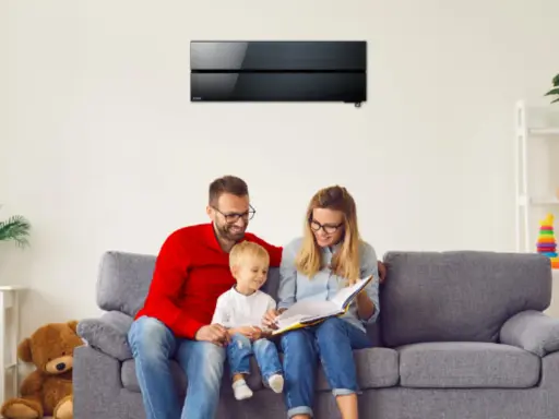 Familia feliz en el sofá, disfrutando de un momento tranquilo bajo el aire acondicionado de bajo consumo.