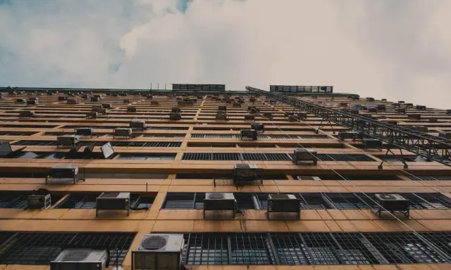 Fachada de edificio con múltiples unidades exteriores de aire acondicionado, mostrando dónde colocar la unidad exterior del aire acondicionado en cada ventana.