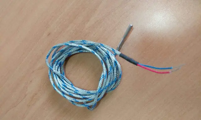 Sonda de temperatura para estufa de pellets, posiblemente indicando un fallo. Cable enrollado con punta metálica y cables rojo y azul.