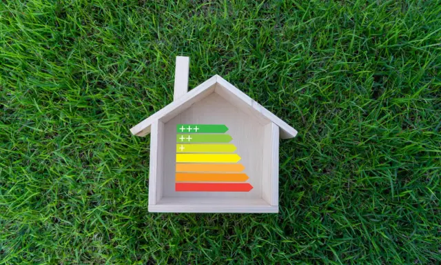 Casa de madera sobre césped con etiqueta de eficiencia energética, ideal para calefacción sostenible.