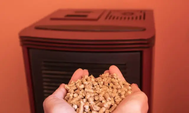 Manos sostienen un puñado de pellets, combustible ecológico para estufas.