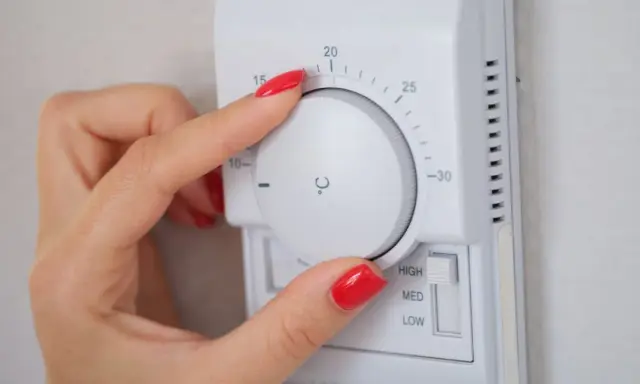 Mano ajustando el termostato para el cálculo de calefacción de la vivienda. La temperatura se muestra en grados Celsius.