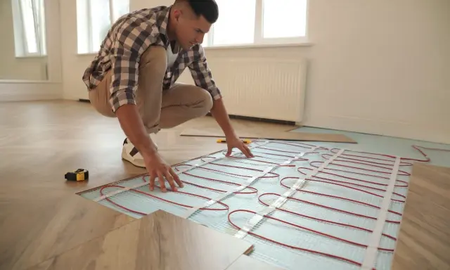 Hombre instalando sistema de calefacción por suelo radiante, mostrando cómo funciona el suelo radiante para un hogar cálido.