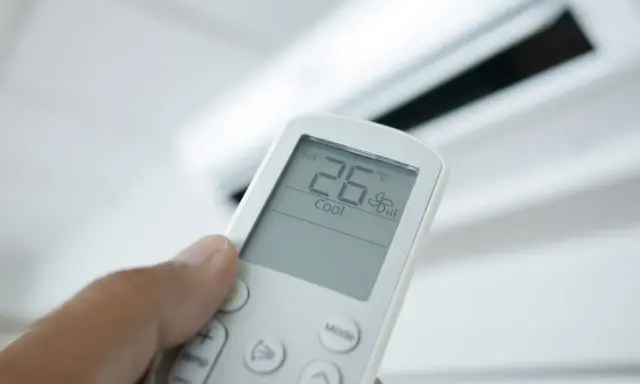Mando a distancia de aire acondicionado mostrando 26°C en modo "Cool". El modo "Dry" deshumidifica el aire.