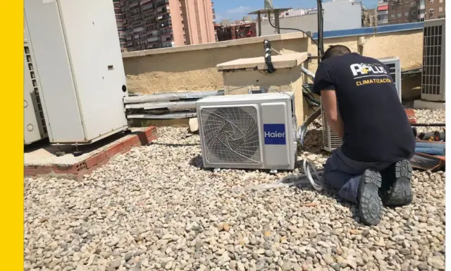 Técnico realizando mantenimiento preventivo de aire acondicionado en una azotea.
