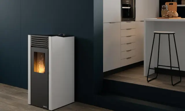 Estufa de pellets sin salida de humos con llama encendida, junto a una barra de cocina moderna.