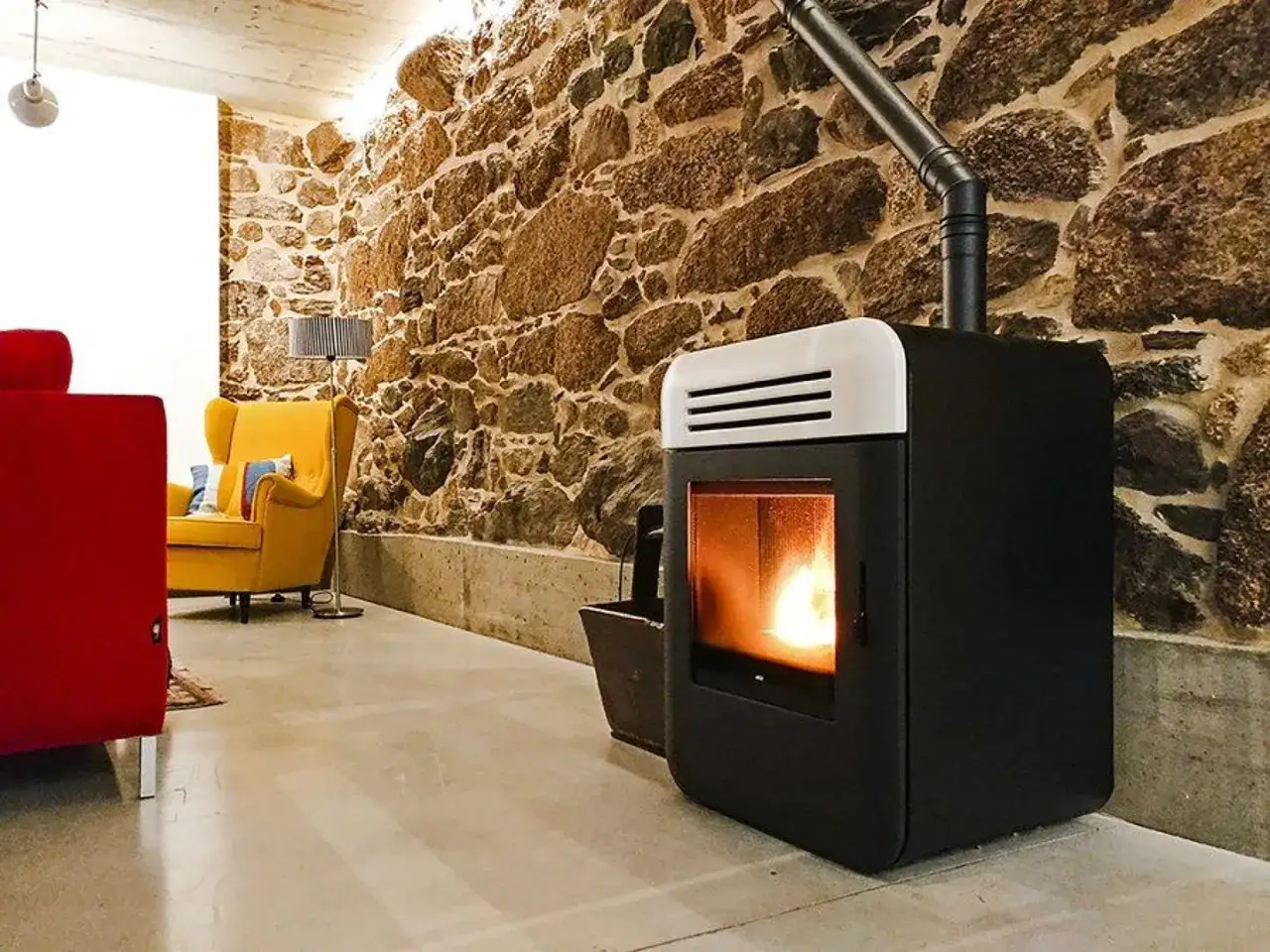 Estufa moderna de pellets, que son los pellets, calienta un sal&oacute;n r&uacute;stico con pared de piedra y muebles coloridos.