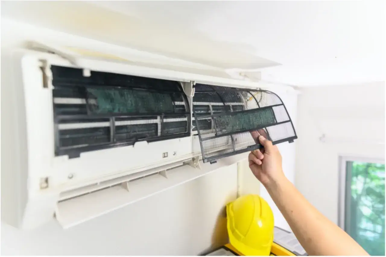 Mano retirando filtro sucio de aire acondicionado. El mantenimiento influye en cuanto dura un aire acondicionado.