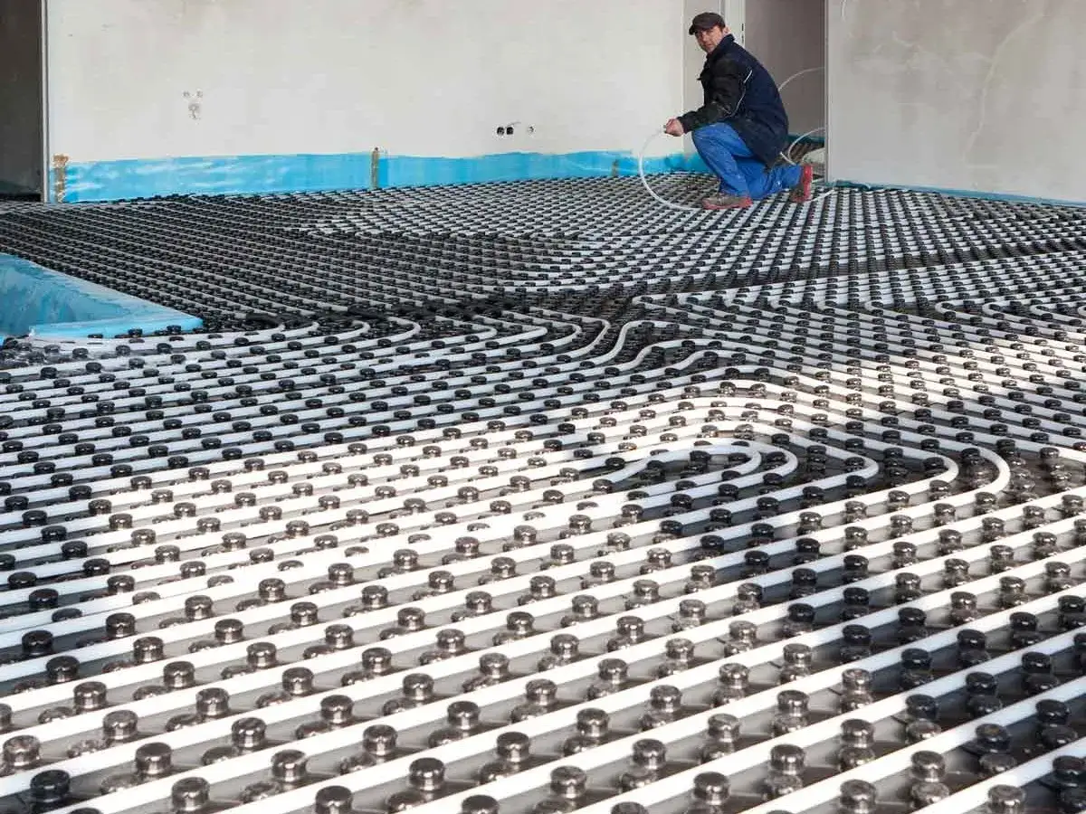 Instalaci&oacute;n de suelo radiante para una futura piscina. Un trabajador coloca las tuber&iacute;as.
