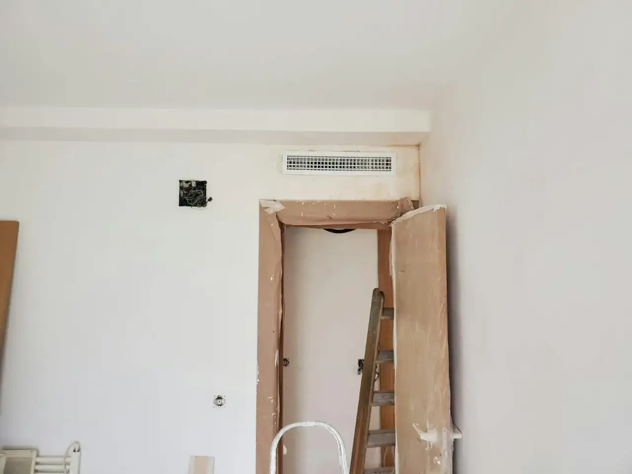 Instalación de aire acondicionado en casa. Ventilación en el techo, puerta en obra con escalera.