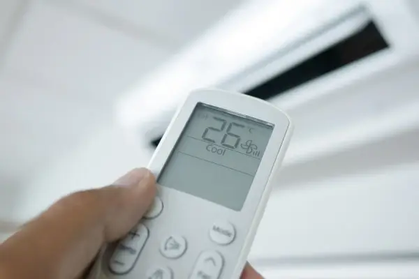 Mando a distancia de aire acondicionado mostrando 26°C en modo "Cool". El modo "Dry" deshumidifica el aire.